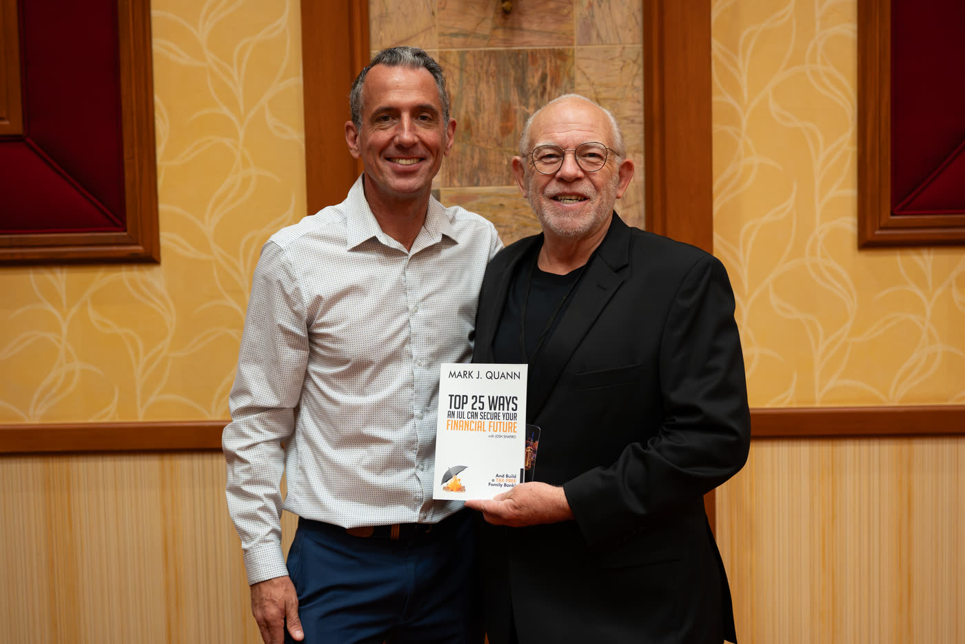 Mark Quann with an attendee holding Top 25 Ways an IUL can Secure Your Financial Future